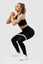 Girl holding squat wearing black invictus seamless set with grey resistance band around thighs
