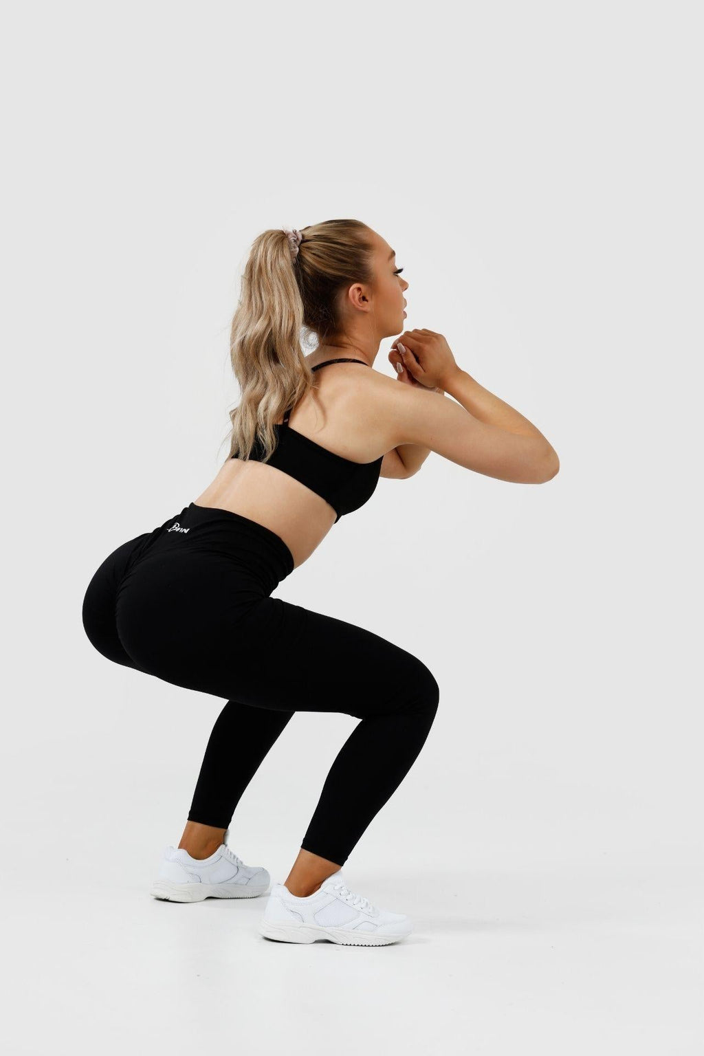 Girl squatting in black intrigue scrunch bum leggings