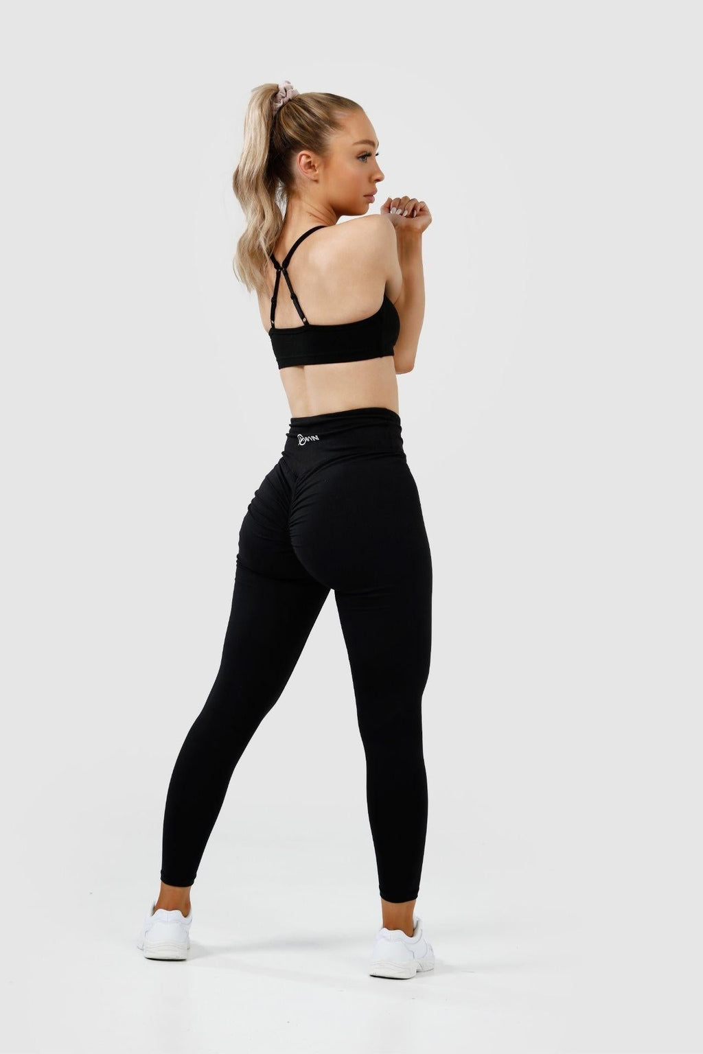 Girl stretching wearing black intrigue scrunch bum leggings, back