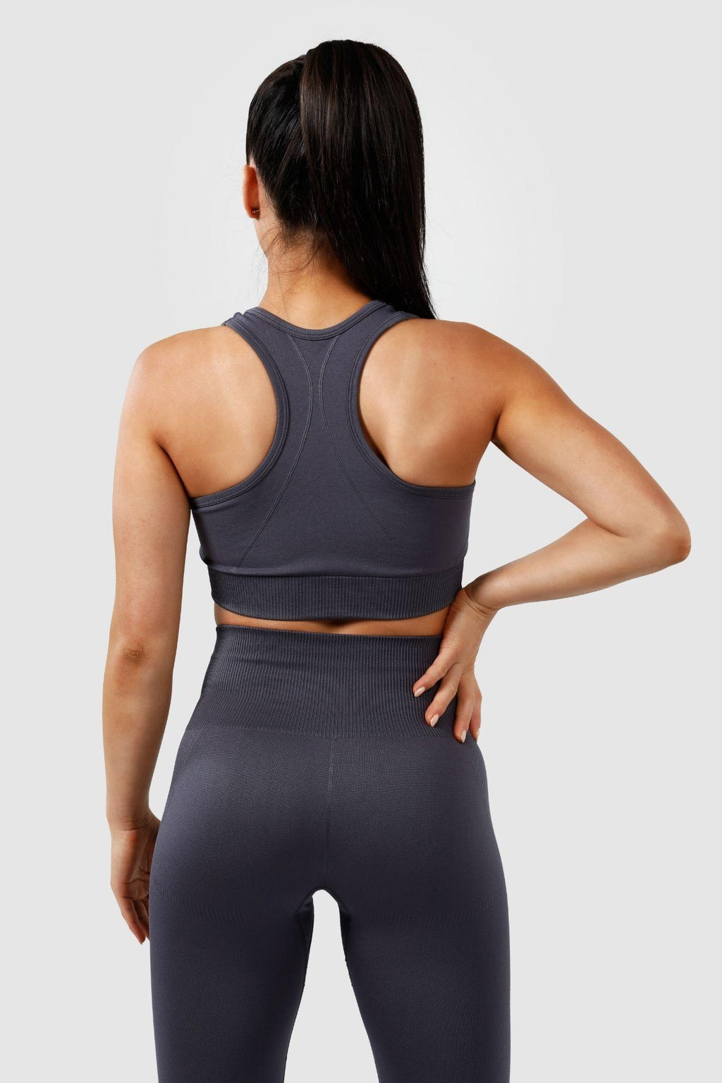 Girl wearing invictus seamless set in charcoal, hand on hip, back 