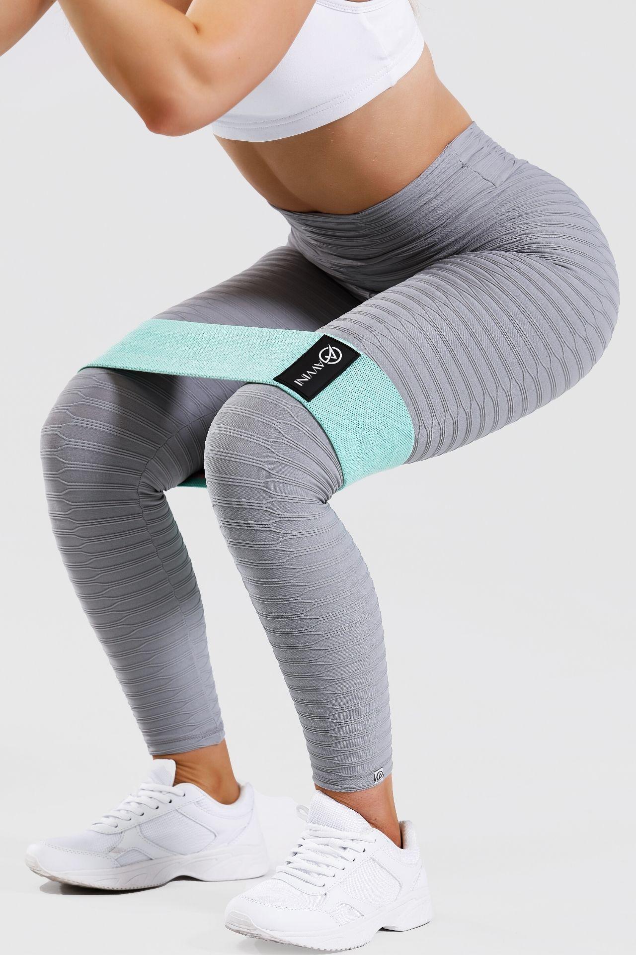 close up girl squatting wearing blue low resistance band around thighs